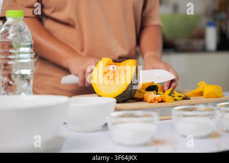 Hausfrauenhände machen Dessert, kochen süße Speisen mit Zutaten wie Kürbis und Zucker in der Küche, zubereiten einer gesunden Mahlzeit mit einem Messer auf dem Schneidebrett Stockfoto