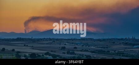Rauch von Waldbränden in den Provinzen Madrid, Ávila und Toledo zieht bei Sonnenuntergang über die Berge, gesehen von Arroyomolinos, Spanien. Stockfoto