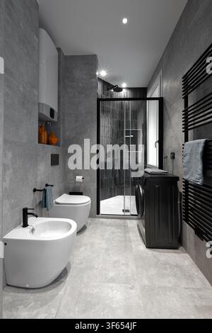 Modernes Badezimmerinterieur mit weißer Tür, hölzernem Waschtischregal und rechteckigem Spiegel, Fenster und Bodenbelag Stockfoto