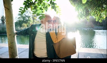 Glückliches Seniorenpaar, das sich im Park am See umgibt Stockfoto