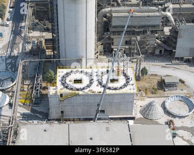 Luftbild der TITAN Cement-Fabrik mit industriellen Betonstrukturen, runden Dachaufbauten und einem hohen Kran in Thessaloniki, Zentralma Stockfoto