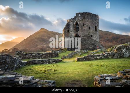 Die Sonne geht hinter Dolbadarn Castle auf, einem historischen Steinturm, der die raue Berglandschaft von Eryri in Llanberis, Nordwales, überblickt Stockfoto