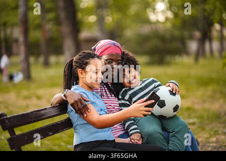 Afroamerikanische alleinerziehende Mutter und Kinder, die im Park ein Selfie machen Stockfoto
