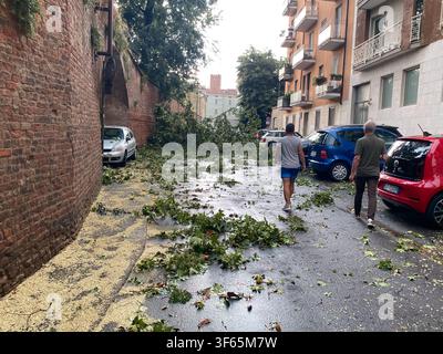 Cremona, Italien, 15. Juli 2026 Straße in Cremona, Lombardei, Italien, bedeckt mit abgefallenen Ästen und Blättern nach einem heftigen Wolkenbruch, zwei Männer gehen Stockfoto