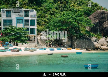 Traditionelle Korbboote, die an einem sandigen Strand bei einer Riverside-Homestay-Anlage festgemacht sind Stockfoto