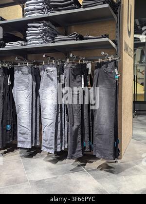 Graue und schwarze Denimjeans, die auf einem Einzelhandelsregal in der Bekleidungsabteilung hängen Stockfoto