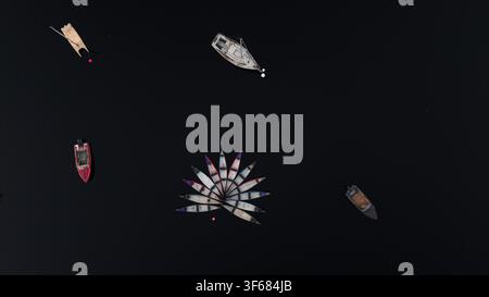 Drohnen-Luftbild von Kanus, die in einem Blumenmuster angeordnet sind, mit festgemachten Booten auf ruhigem Seewasser, minimalistische Sommer-Freiluft-Erholungsszene Stockfoto