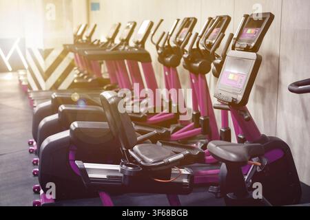 Cardio-Zone mit Fitnessbikes und Laufbändern in einem sonnendurchfluteten Fitnessstudio, selektive Fokussierung Stockfoto