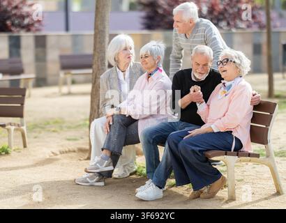Seniorenfreunde plaudern miteinander, während zwei von ihnen flirten Stockfoto