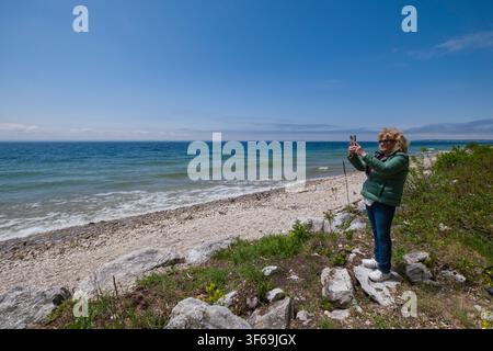 Entlang der Lake Shore Drive auf Mackinac Island aufgenommen, zeigt diese Szene die raue Schönheit der Küste Michigans. Eine Frau genießt einen Moment des Dokumentierens Stockfoto