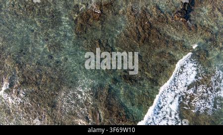 Eine Luftaufnahme zeigt die dramatische Küste des Mauna Lani Resorts an der Südküste von Kohala auf Hawaii. Wellen brechen gegen dunkles, zerklüftetes Lavagestein fo Stockfoto