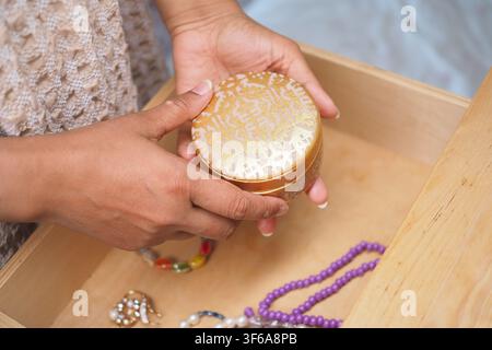 Person hält eine runde Goldschachtel in einer Holzschublade Stockfoto