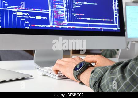 Programmiererhände, die auf einer Computertastatur tippen, mit Code, der auf dem Monitor angezeigt wird, Softwareentwicklung und Technologie, eine Person, die ein kariertes Hemd trägt Stockfoto