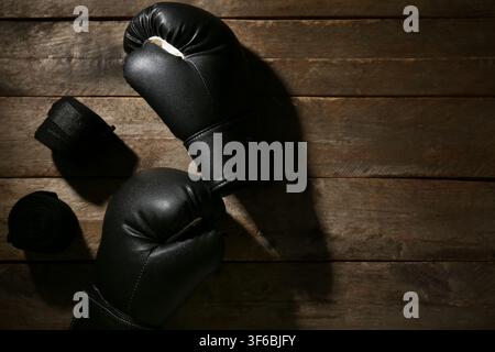 Paar schwarze Boxhandschuhe mit Handgelenksbändern auf Holzuntergrund Stockfoto
