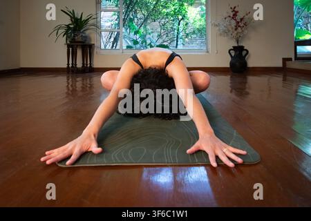 Frau praktiziert Yoga in der Kindergestalt Stockfoto