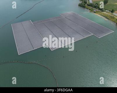 Luftaufnahme einer großen schwimmenden Solarfarm-Anlage, die auf einem ruhigen See installiert wurde, mit Reihen von Photovoltaikmodulen auf schwimmenden Plattformen, umgeben von Stockfoto