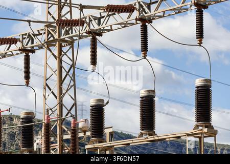 Stahlgitter-Portalkonstruktion einer Hochspannungsunterstation mit keramischen Isolatorsträngen und Buchsen, die an Stromkabel angeschlossen sind. Stockfoto