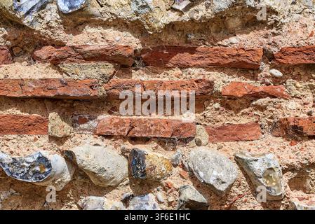 Detaillierte Nahaufnahme, die rote Tonfliesen und gekniffenen Feuerstein zeigt, die in altem Kalkmörtel am Burgh Castle Römischen Fort in Norfolk, England, eingebettet sind. Stockfoto