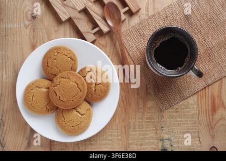 Direkte Ansicht von oben auf eine Tasse Kaffee und Haferflockenkekse auf altem Holzgrund Stockfoto