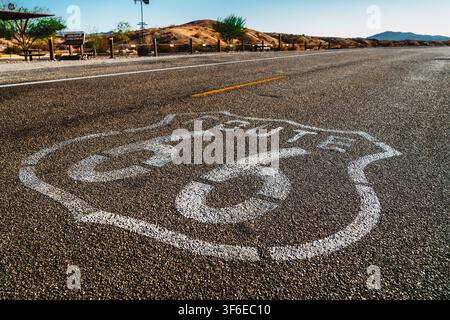 Historisches Route-66-Schild, das auf Asphaltstraße in sonniger Wüstenlandschaft gemalt ist, amerikanischer Südwesten Stockfoto