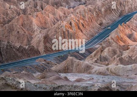 Luftaufnahme einer sich windenden asphaltierten Straße, die raues Hochland-Kanyon-Terrain in der Atacama-Wüste, Chile, durchquert und abgelegenes Abenteuerreisen zeigt Stockfoto
