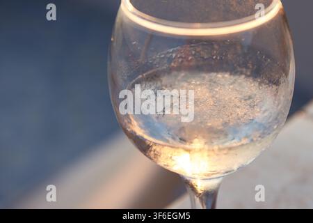 Nahaufnahme eines Glases mit traditionellem griechischem Ouzo, in dem schmelzendes Eis den charakteristischen trüben Louche-Effekt und kalte Kondensation auf der Oberfläche zeigt. Stockfoto