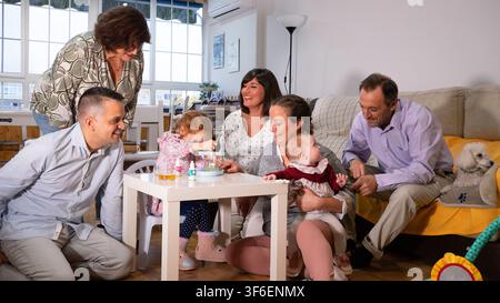 Mehrere Generationen von Menschen, die drinnen zusammenkommen, lächeln und die Gesellschaft des anderen genießen Stockfoto