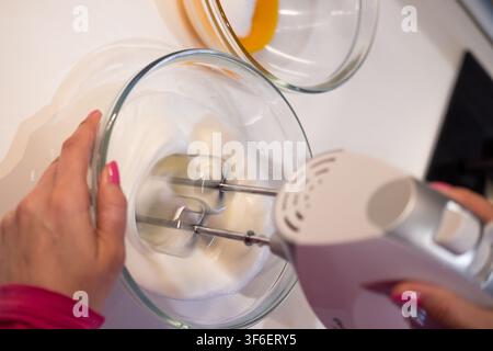 Frau schlägt Eiweiß mit einem elektrischen Mixer zum Backen Stockfoto