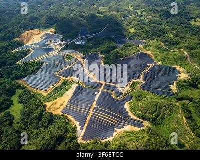 Luftbild des Sikatuna-Solar-Kraftwerks mit umfangreichen Solarpanel-Arrays, die in die hügelige Landschaft integriert sind, mit üppiger grüner Vegetation in der Umgebung Stockfoto