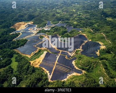 Luftaufnahme des Sikatuna-Solarkraftwerks mit umfangreichen Feldern von Solarpanelen, die in die hügelige, bewaldete Landschaft der Region integriert sind, Sika Stockfoto