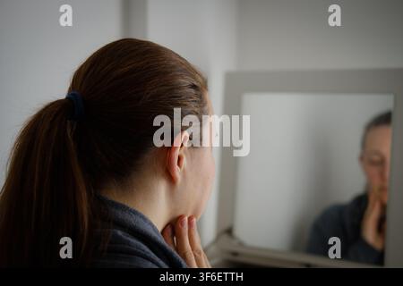 Frau betrachtet ihr Spiegelbild, denkt und introspektiert Stockfoto