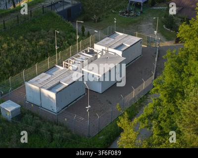 Luftaufnahme eines Batterie-Energie-Speichersystems mit weißen Containern, Sicherheitszaun und Lichtmasten in einer ländlichen Gegend in Polen Stockfoto