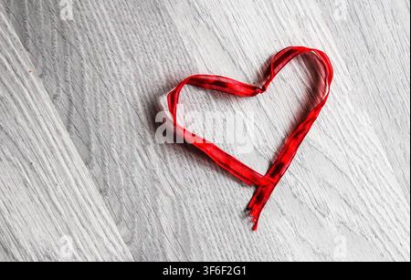 Rotes Herz aus Seil auf einer Holzoberfläche, das Liebe, Romantik und den Valentinstag symbolisiert. Stockfoto
