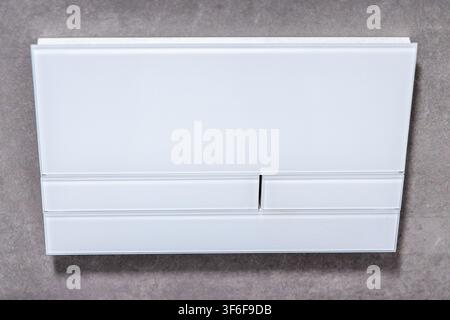 Eine saubere und zeitgemäße Dual-Spülplatte für versteckte Spülkästen, mit einer eleganten weißen Glasoberfläche und minimalistischem Design Stockfoto