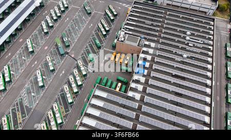 Luftaufnahme einer modernen öffentlichen Verkehrseinrichtung mit mehreren Elektrobusse, die in Reihen geparkt sind, und Solarpanelen, die auf dem Dach des Depots in S installiert sind Stockfoto