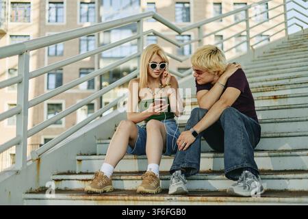 Menschen, die auf Treppen sitzen und Musik auf dem Smartphone hören Stockfoto