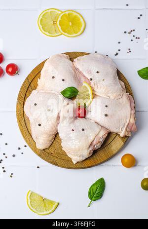 Rohe Hähnchenschenkel mit Gemüse auf einem Holzbrett, auf weißem Hintergrund. Stockfoto