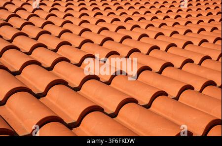 Wiederholtes Wellenmuster roter Terracotta-Dachziegel auf einem mediterranen Gebäude unter sonnigen Bedingungen. Stockfoto