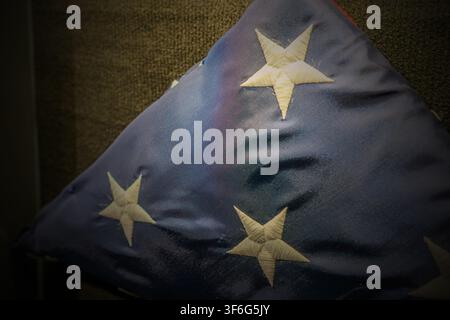 Eine zeremoniell gefaltete amerikanische Flagge, die in einer dreieckigen Form dargestellt ist und das blaue Feld mit bestickten weißen Sternen zeigt. Die Flagge ist positioniert agai Stockfoto