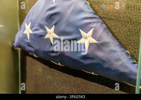 Eine zeremoniell gefaltete amerikanische Flagge, die in einer dreieckigen Form dargestellt ist und das blaue Feld mit bestickten weißen Sternen zeigt. Die Flagge ist positioniert agai Stockfoto