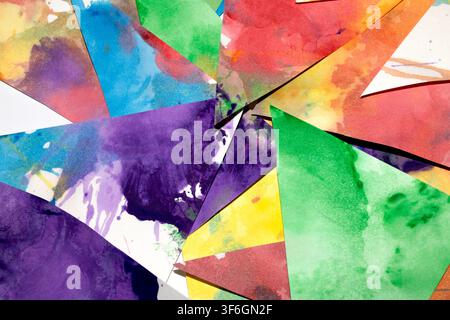 Dreiecksgeschnittenes Papier mit Farbspritzern abstrakter Regenbogenhintergrund Malerei kreative Formen Stockfoto