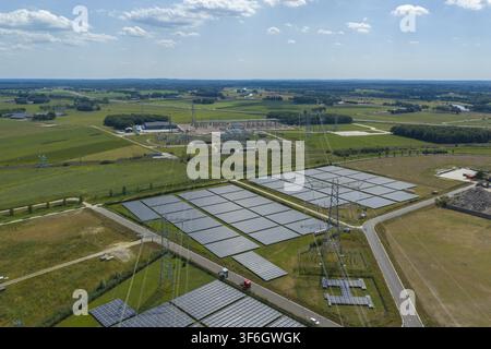 Luftaufnahme einer großen Solarfarm mit Reihen von Photovoltaik-Paneelen und einem Umspannwerk, das durch Hochspannungsleitungen in Zwolle, Overijssel, verbunden ist Stockfoto