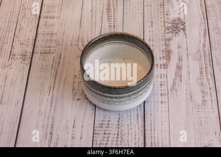 Handgefertigte Keramiktasse mit gesprenkelter Glasur im Inneren und metallischem Rand auf Holz Stockfoto