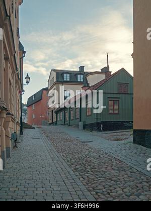 Stockholm, Schweden - 29.10.2016: Traditionelles grünes Holzhaus und farbenfrohe Stuckgebäude entlang einer schmalen Kopfsteinpflastergasse bergauf Stockfoto
