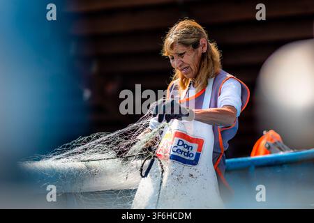 Eine chilenische Frau entwirrt Fischernetze in Caleta Portales, einem traditionellen Fischereihafen in Valparaíso, Chile. Stockfoto