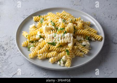 Fusilli-Pasta-Salat mit Fetakäse und frischer Petersilie, serviert auf einem grauen Teller Stockfoto
