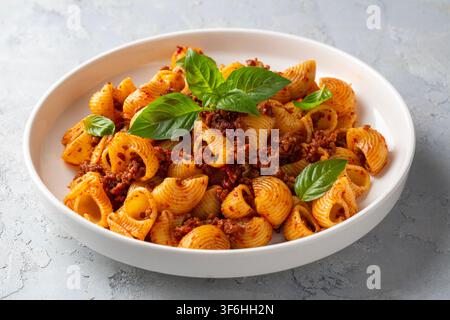 Italienische Pipe Rigate Pasta mit Bolognese-Sauce und frischen Basilikumblättern - Manti makarna Stockfoto