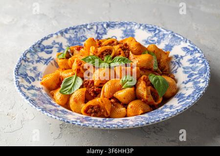 Italienische Pipe Rigate Pasta mit Bolognese-Sauce und frischen Basilikumblättern - Manti makarna Stockfoto