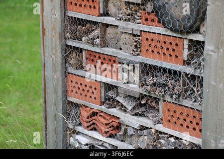 Holz-Insektenhotel in üppigem grünem Gras an einem sonnigen Sommertag im Norden Schwedens, das die Biodiversität und Lebensräume von Bestäubern fördert. Stockfoto