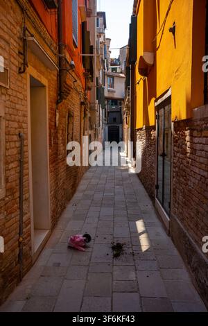 Venedig, Italien - 19. Juni 2026: Vertikale Perspektivenaufnahme einer klassischen ruhigen Straße in Venedig mit lebendigem orangefarbenem Putz, alten Ziegelmauern und c Stockfoto